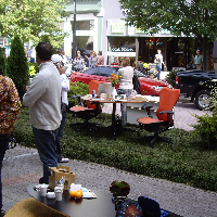 People on a sidewalk by a table with games and coffee